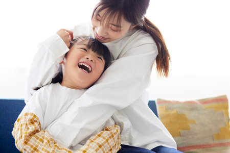 Happy Japan mother and child playing cheerfully on sofaの写真素材