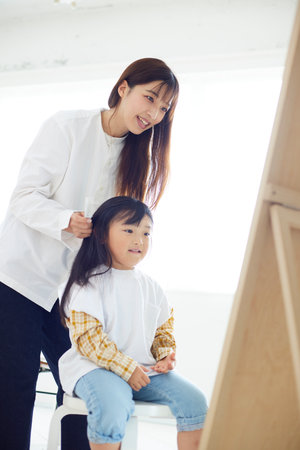 Japan mother and daughter doing children's hair and makeup in the living roomの写真素材