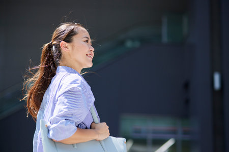 Smiling Japan businesswoman walking outdoors in summerの写真素材