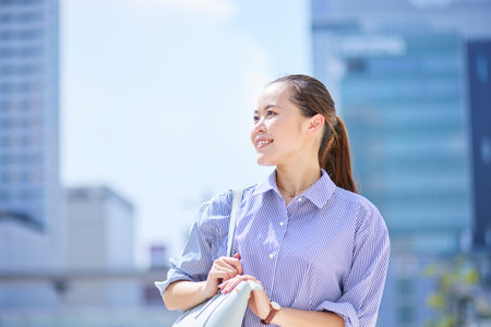 Japan businesswoman smiling in summer business districtの写真素材