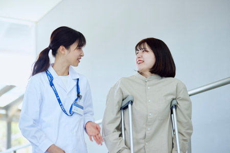 A female doctor watching over a patient undergoing rehabilitation in a hospitalの写真素材