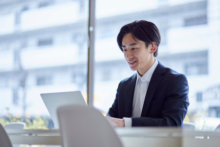 Young Japan businessman in suit working on computer in officeの写真素材