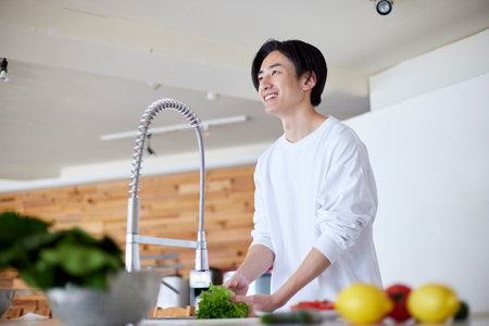 Young Japan man doing household chores in kitchenの写真素材