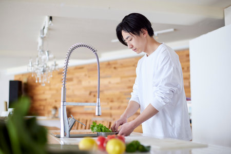 Young Japan man doing household chores in kitchenの写真素材