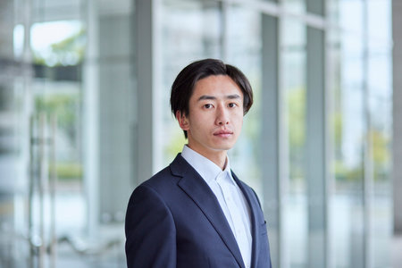 Young Japan businessman in suit with office buildingの写真素材