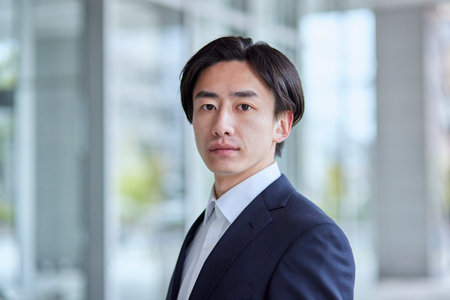Young Japan businessman in suit with office buildingの写真素材