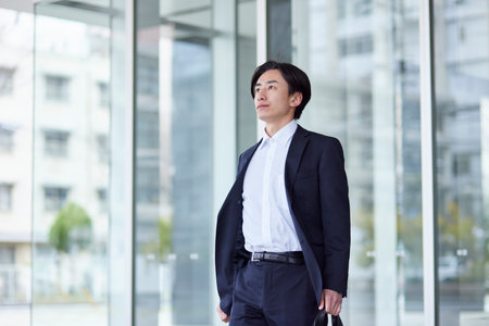Young Japan businessman in suit with office buildingの写真素材