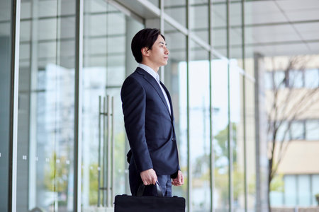 Young Japan businessman in suit with office buildingの写真素材