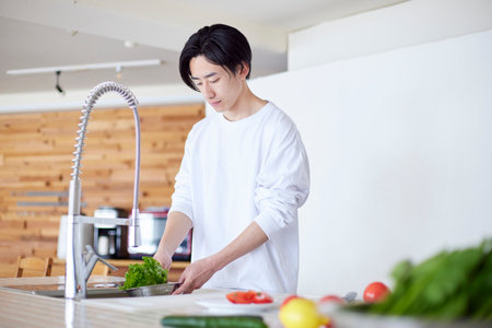 Young Japan man doing household chores in kitchenの写真素材