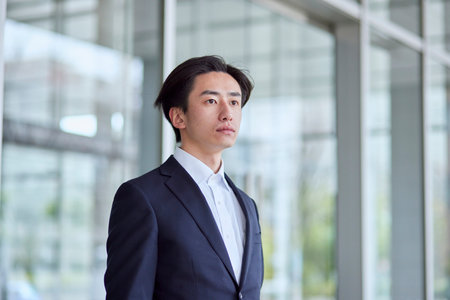 Young Japan businessman in suit with office buildingの写真素材