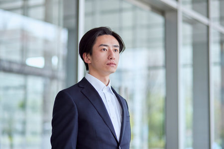 Young Japan businessman in suit with office buildingの写真素材