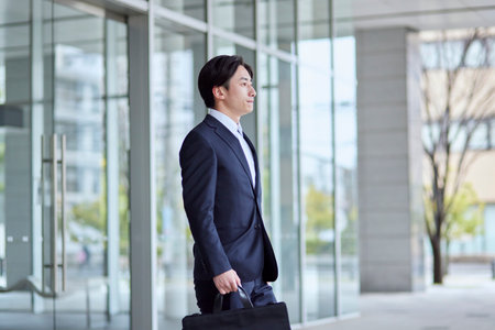 Young Japan businessman in suit with office buildingの写真素材