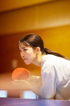 Japan woman wearing sportswear practicing table tennis in gymnasiumの写真素材