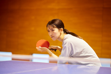 Japan woman wearing sportswear practicing table tennis in gymnasiumの写真素材
