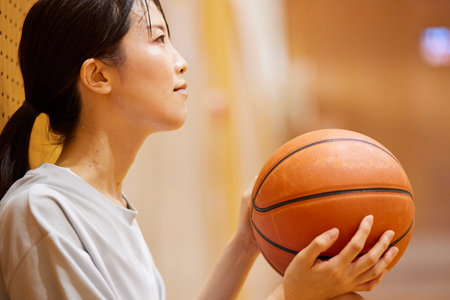 Japan woman in sportswear practicing basketball in gymnasiumの写真素材