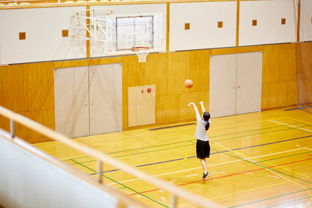 Japan woman in sportswear practicing basketball in gymnasiumの写真素材