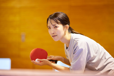 Japan woman wearing sportswear practicing table tennis in gymnasiumの写真素材