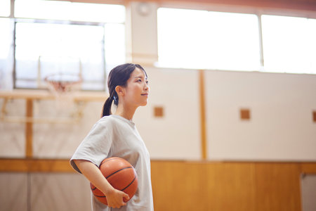 Japan woman in sportswear practicing basketball in gymnasiumの写真素材