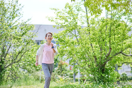 Senior woman wearing sportswear enjoying running in fresh spring greeneryの写真素材