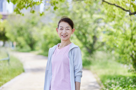 Japan senior woman wearing sportswear in fresh spring greeneryの写真素材