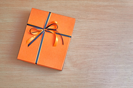 Elegant box with an orange lid for a gift tied with a black and orange ribbon with a beautiful bow.の写真素材