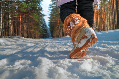 Leg woman in winter shoes walking on the snow in a winter park. Closeup outsole of warm boot.の写真素材