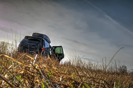 Off-road car on the field with burning lights. Traces of tires on the grass.の写真素材