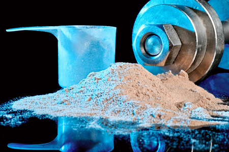 Scoop and protein mixture on a background of a metal dumbbell.の写真素材