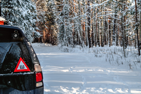 Car in the winter forest on snow road. A sticker on the car glass - studded wheels. Rear view.の写真素材