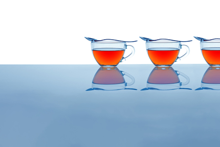 Elegant glass cups with tea and spoons laid on top.の写真素材