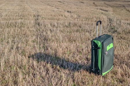 Large suitcase standing on a yellow field.の写真素材