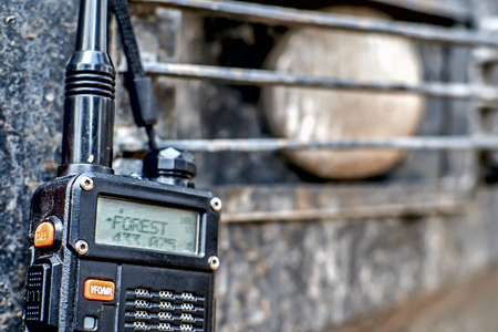 A walkie-talkie with the words on the screen Forest, against the dirty off-road lights in front bumper 4x4 car.の写真素材