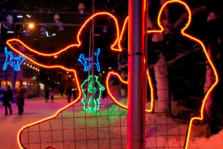 Concept of the holiday, entertainment. Festive night illumination in winter park.  Glowing silhouettes of people. Multicolored garlands. Copy space.の写真素材