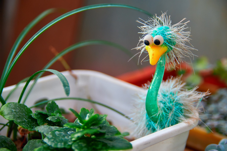 Concept lifestyle design. Green bird toy in pot with plants in the room.の写真素材