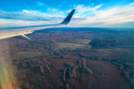 View From Airplane. Beautiful landscape of forests and fields with a bird's-eye view. Wing Through Plane passenger Window During Flight. Clouds and skyline horizon panoramic view.の写真素材