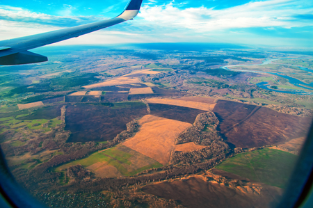 View From Airplane. Beautiful landscape of fields with a bird's-eye view. Wing Through Plane passenger Window During Flight. Clouds and skyline horizon panoramic view.の写真素材