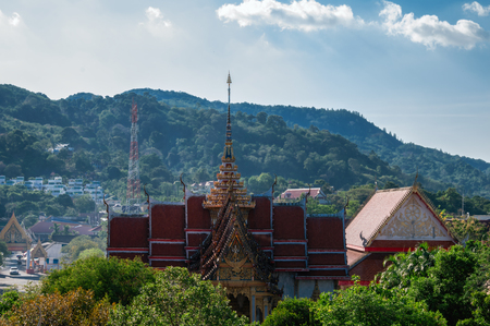 Buddhist Wat temple Chalong (Wat Chayyatararam) against the blue sky and mountainsの写真素材