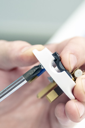 Men's hand assembled electrical plug. Fingers hold the screwdriver and tighten the screw. Copy space. Repair concept.の写真素材