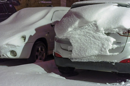 Cars are covered with snow after night of snowfall. Snow storm covered cars with thick layer of snow. Heavy snowfall created problems for drivers. Winter snowstorm. Snow cover.Night snowfallの写真素材