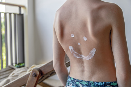 Smiley painted sunscreen on the back small child. Concept of protection against harmful ultraviolet radiation.の写真素材