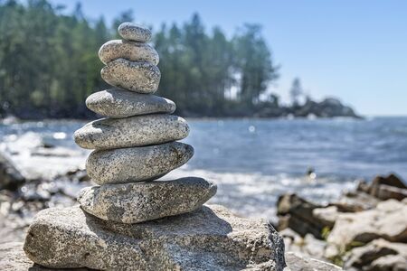 Pyramid of stones, stone sculpture, against the sky and water. Cairn stones piled in hill.の写真素材