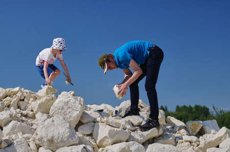 Dad and son are looking for fossils. My family hobby is paleontology. A family walks on a pile of limestone stones against the background of a blue sky on a sunny summer day.のeditorial素材