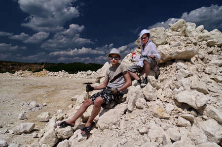 Boys are looking for fossils in a pile of limestone stones. A sunny summer day.の写真素材