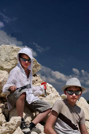 Boys are looking for fossils in a pile of limestone stones. A sunny summer day.の写真素材