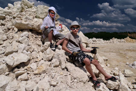 Boys are looking for fossils in a pile of limestone stones. A sunny summer day. hobby is paleontology.の写真素材