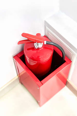 Hand-held fire extinguisher stands in the corner of the office. Red fire extinguisher in box against the white wall.の写真素材