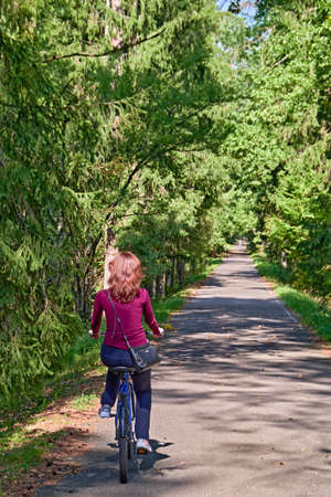 Girl on a bicycle rides through a summer park. Rear viewの写真素材
