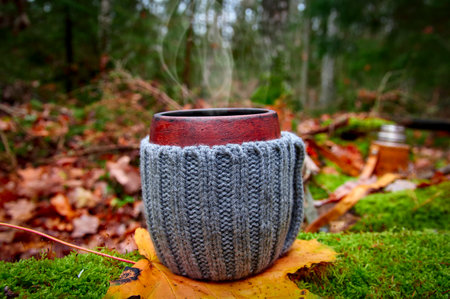 Picnic in the autumn forest. Clay mug of hot tea stands on green moss against the background of the autumn forestの写真素材