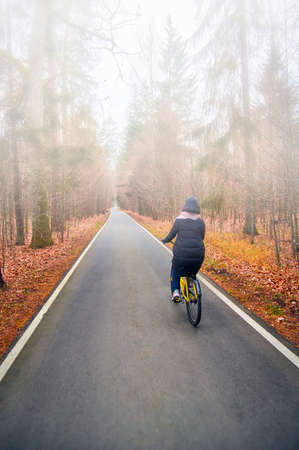 Girl on bicycle rides in autumn foggy park.の写真素材