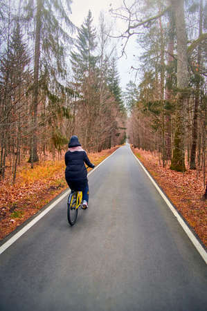 Girl on bicycle rides in autumn foggy park.の写真素材